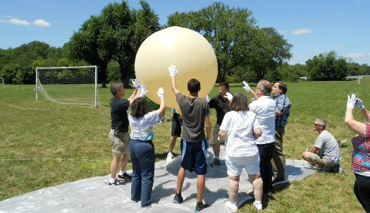 A group of teachers are using a balloon outside during a Teachers Institutes session.